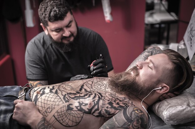 Meester tatoeëerder doet tattoo foto in de salon