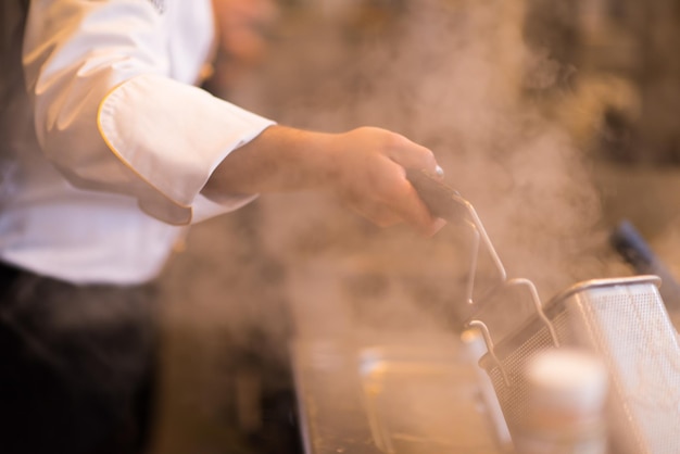 Meesterkok bereidt voedsel, frituurt in frituurpan. Verkoop en food concept