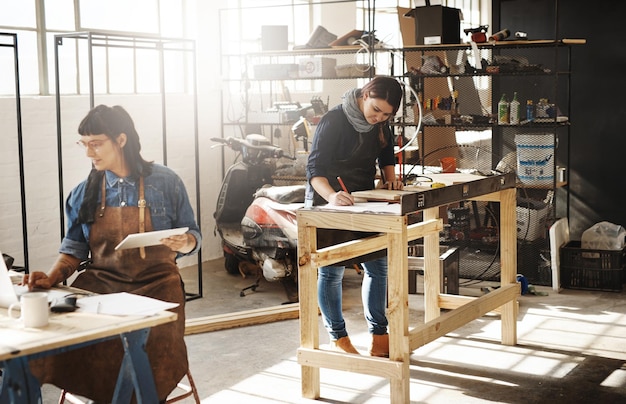 Meesterwerken maken van hout Bijgesneden opname van twee aantrekkelijke jonge creatieve vrouwelijke ambachtslieden die in hun atelier werken