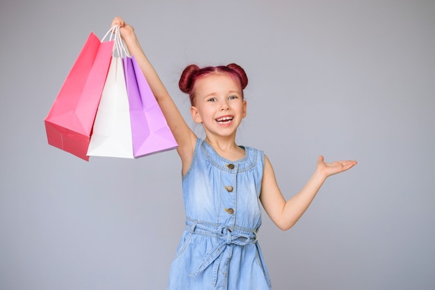 Meet the discounts. Happy little baby girl smiles with paper shopping bags.