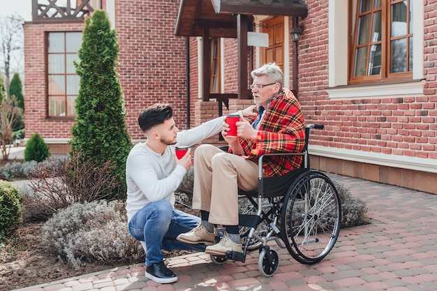 Meet of family! Son with his father holding coffe and talking with dad