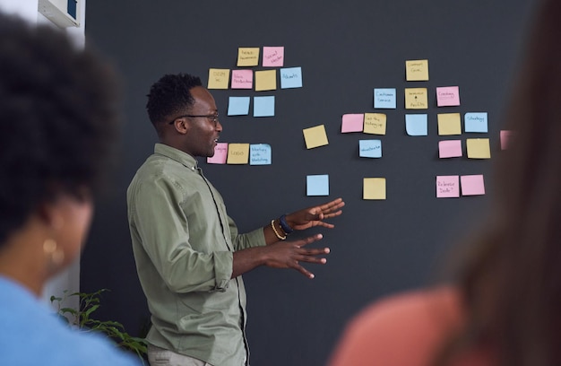 Meeting brainstorming and planning with team black man speaker sticky note and leader in presentation Collaboration teamwork and people in strategy workshop ideas with presenter and audience