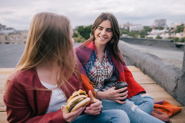 Photo meeting friends with takeaway junk food on roof. unusual places for rest and parties, communication and sharing time together, inviting and joyful atmosphere