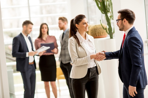 Meeting of group of businesspeople in the office standing in front of  large window