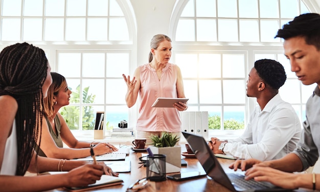 Photo meeting planning and training with a female leader manager or boss in the boardroom for a workshop or seminar teamwork tablet and communication with a business woman and her team in discussion