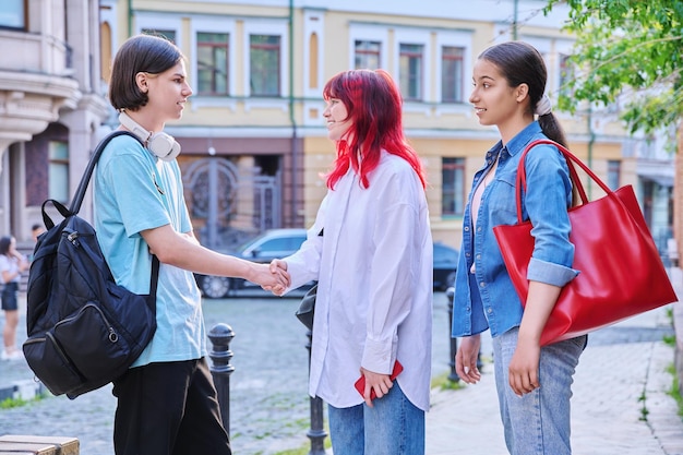 街の通りで10代の友達と出会い 笑って話す 若い女性と男性 若者のコミュニケーション 友情 感情 高校のコンセプト