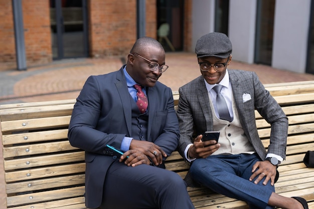 meeting of two African businessmen in suits on a bench with mobile phones