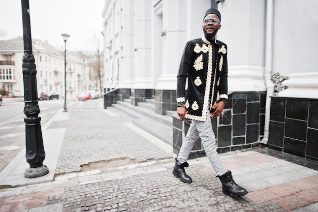 Mega stylish african man in traditional jacket pose Fashionable black guy in hat and sunglasses with cigar in hand