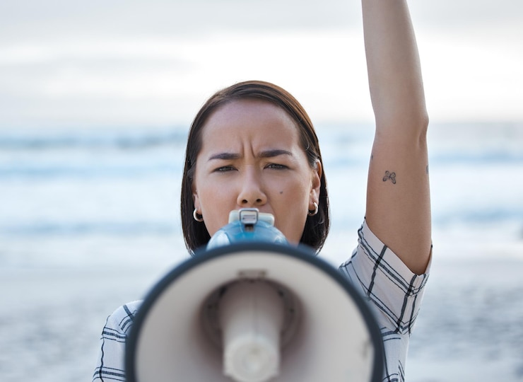 Photo 氣候變化抗議和亞洲女性在海灘上抗議環境全球暖化和阻止海洋污染拯救地球運動和憤怒的女性在喇<unk>上喊叫
