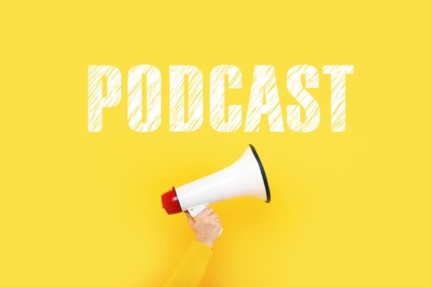 Megaphone in hand and inscription podcast on a yellow wall