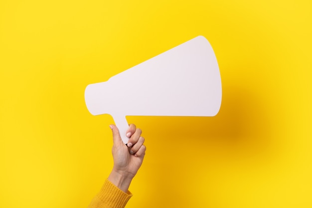 Megaphone in hand over yellow background