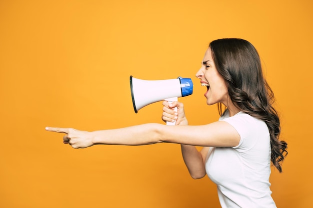 A megaphone in the right hand of an angry girl with long curly hair clothed in basic white T-shirt