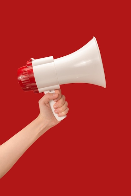 Megaphone in woman hands on a red background Copy space