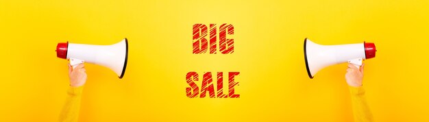 Photo megaphones in hands and inscription big sale on yellow