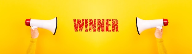megaphones and inscription winner on a yellow background, panoramic image