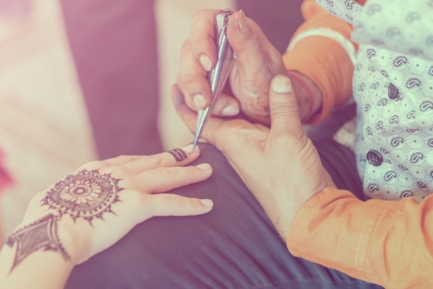 Мехенди Женщина рисует на руке красивый узор в тонах