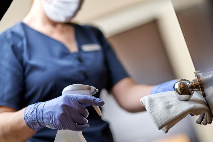 Foto meid met masker doet de deurklink in het hotel desinfecteren