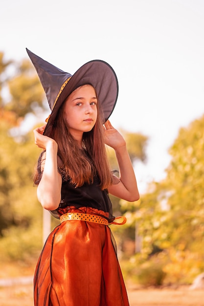 Meisje 11 jaar oud tegen de achtergrond van de herfstnatuur. Klein meisje in Halloween kostuum, herfst.