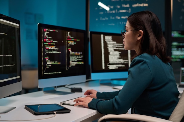 Meisje als IT-ontwikkelaar die code schrijft in blauw licht