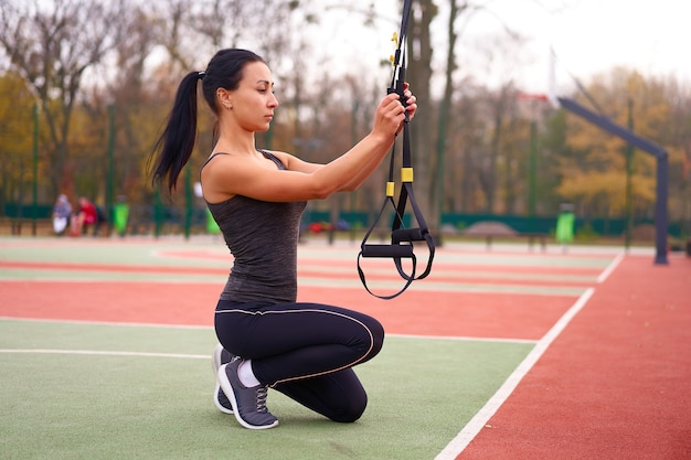 Meisje atleet training met behulp van trx op sportground