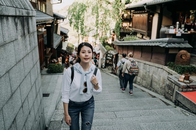 meisje backpacker glimlachend klimmen traplopen in sannen zaka straat. veel buitenlandse toeristen bezoeken de beroemde attractie Kyoto Japan. mooie vrouw reiziger vrolijk een bezoek aan de oude stad in Japanse stijl