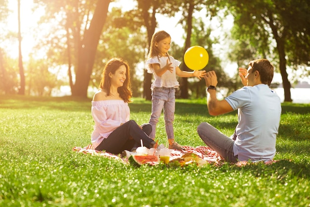 Meisje ballon spelen met ouders in het park op zonnige dag