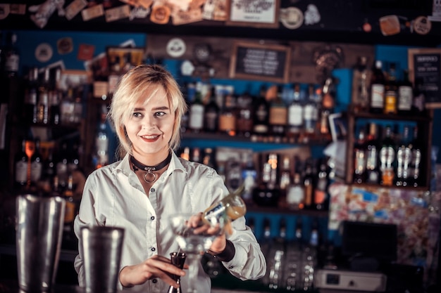 Meisje barman formuleert een cocktail op de saloon