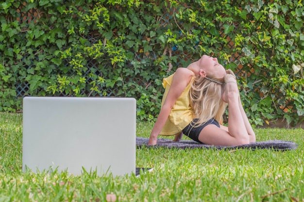 meisje beoefenen van gymnastiek thuis, online video kijken op laptop.