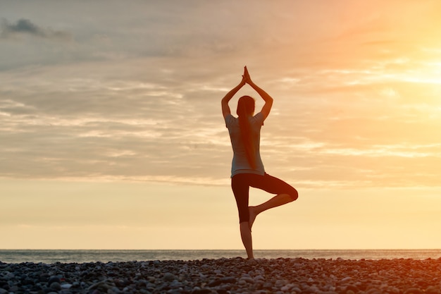 Meisje beoefenen van yoga aan de kust
