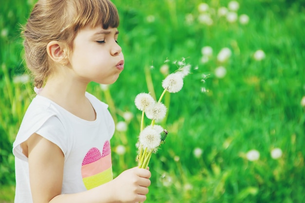 Meisje blaast paardebloemen in de lucht selectieve focus