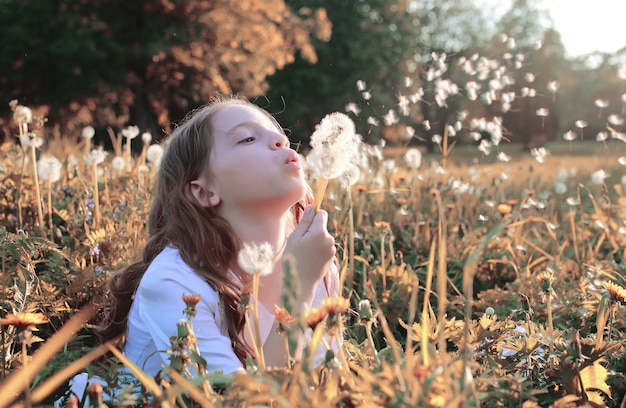 Meisje blaast zaden van een bloempaardebloem in de herfstmiddag