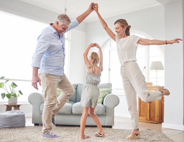 Meisje dans met grootouders op woonkamer veel plezier en gelukkige tijd in huis Senior man glimlach in huis met vrouw en kind dansen en samen spelen in hun lounge bij het ouderlijk huis