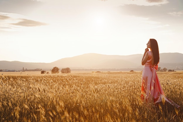 Meisje dansen in een veld in een mooie roze jurk bij zonsondergang