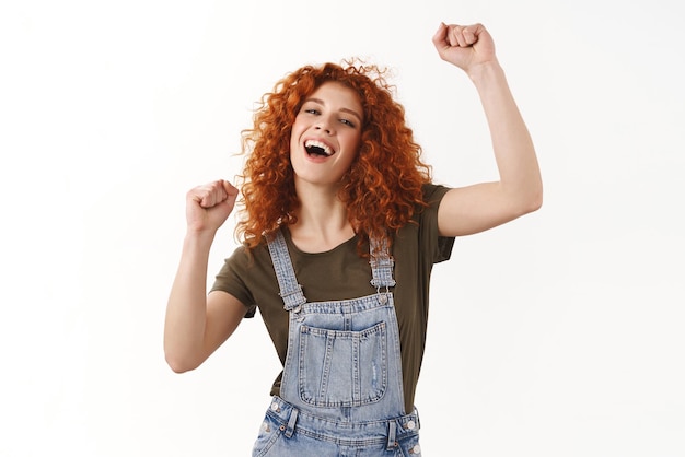 Meisje dansen levendig geweldig concert plezier zorgeloos enthousiaste jonge krullendharige roodharige vrouw handen omhoog lucht genieten van cool partij bewegend lichaam op muziek ritme staande witte achtergrond