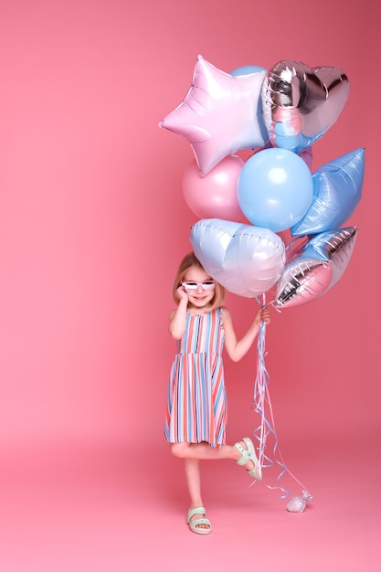 Meisje danst met ballonnen op roze oppervlak