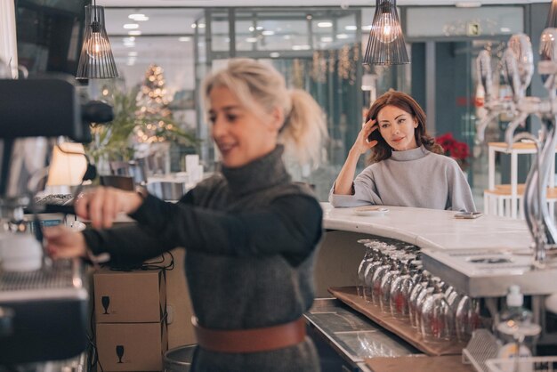 Foto meisje dat aan de toonbank van een koffiewinkel zit te wachten op een kop koffie