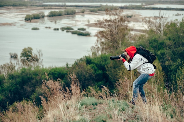 Meisje dat aard fotografeert die zich op de rand van de klip bevindt. Koude wind.