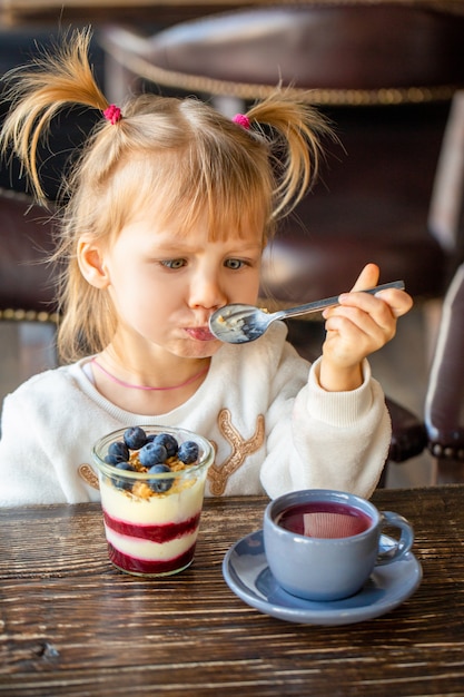 Foto meisje dat dessert met bessen eet en ogen kruist.