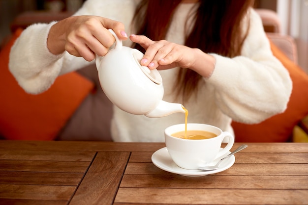 Meisje dat detox-kruidenthee drinkt in café Witte kop duindoornthee op tafel in café