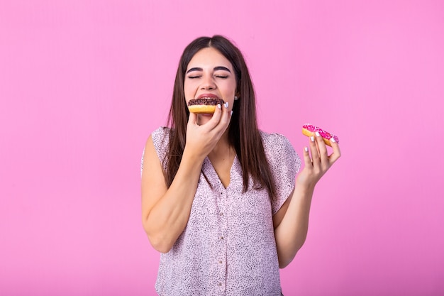 meisje dat donuts eet die over roze wordt geïsoleerd