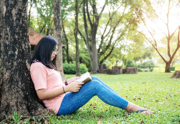 Meisje dat een boek in park leest.