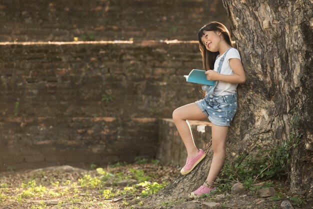 Meisje dat een boek leest onder grote boom