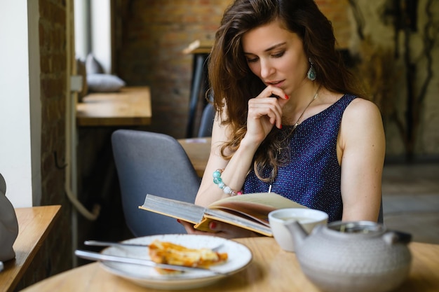 Meisje dat een boek leest tijdens het ontbijt in een coffeeshop