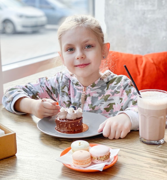 Meisje dat een cake eet in een koffie