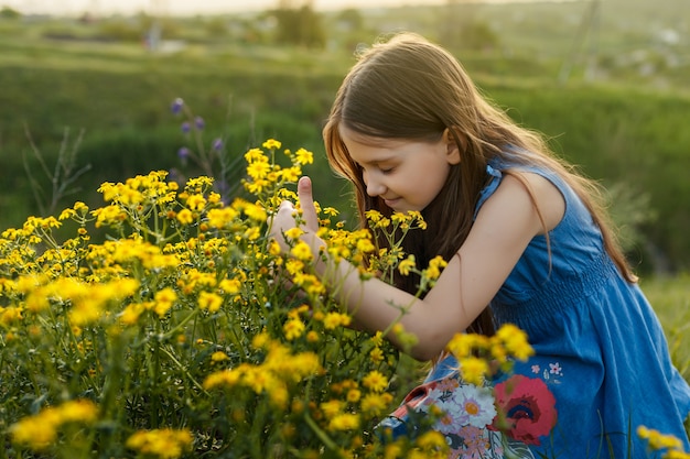 Meisje dat een gele bloem ruikt