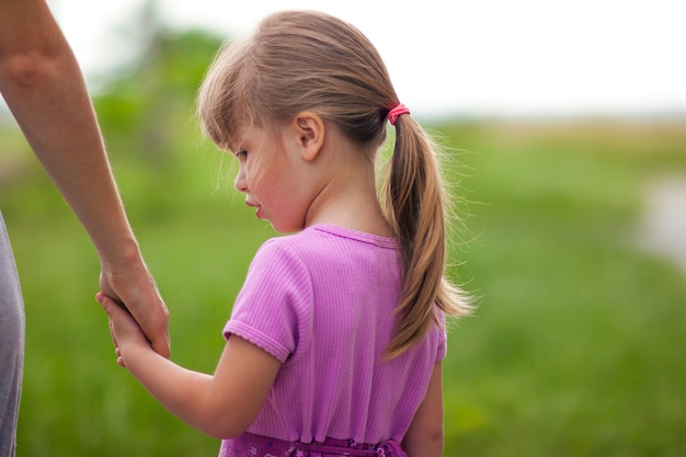 Meisje dat een hand van haar moeder houdt. Familierelaties conce