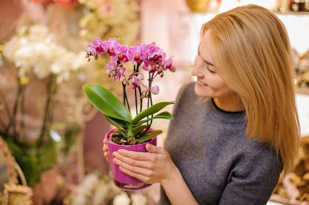 Meisje dat een mooie roze orchidee in pot houdt