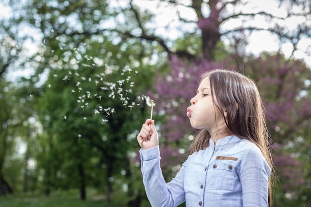 Meisje dat een paardebloem blaast