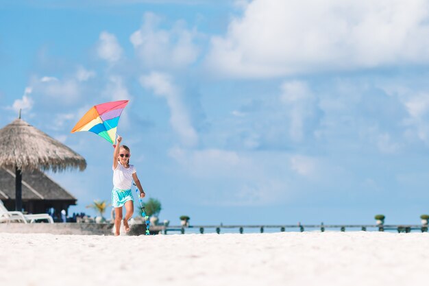 Meisje dat een vlieger op het strand met turquiosewater vliegt