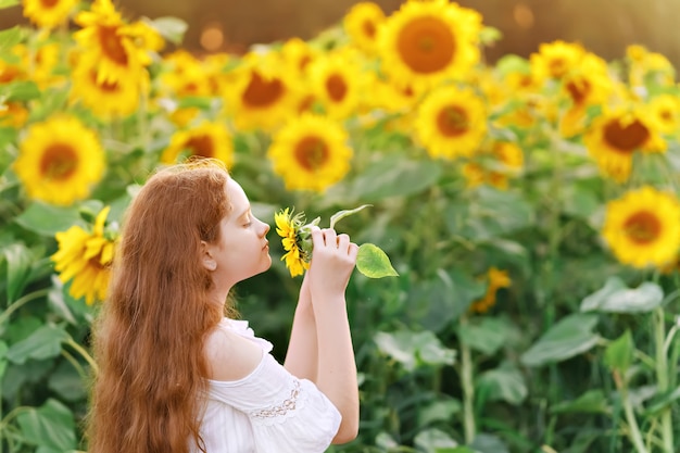 Meisje dat een zonnebloem ruikt